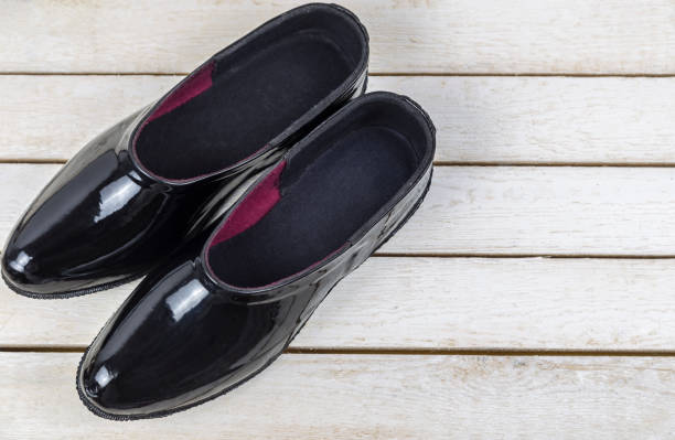 istock Black pair rubber galoshes stand on wooden boards 1074130526