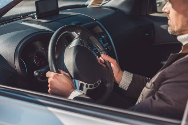 istock Man sitting and driving car in daytime 1074130762