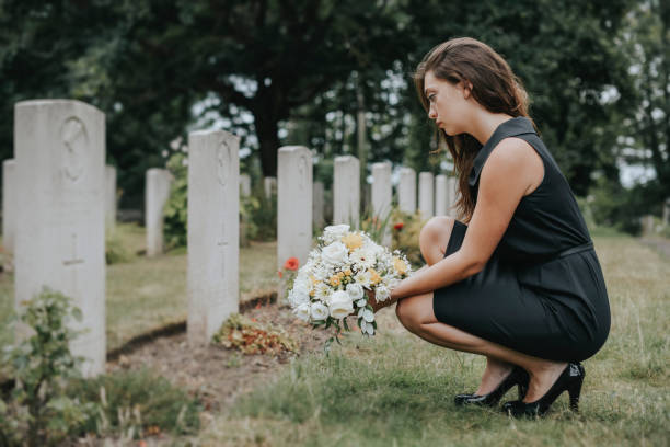 istock Young widow laying flowers at the grave 1074136280