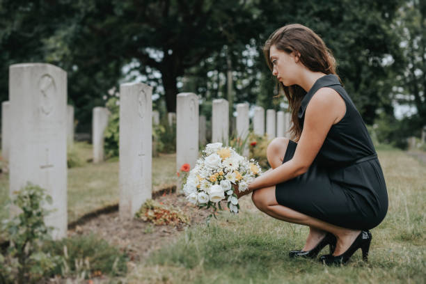 Young widow laying flowers at the grave Young widow laying flowers at the grave widow stock pictures, royalty-free photos & images