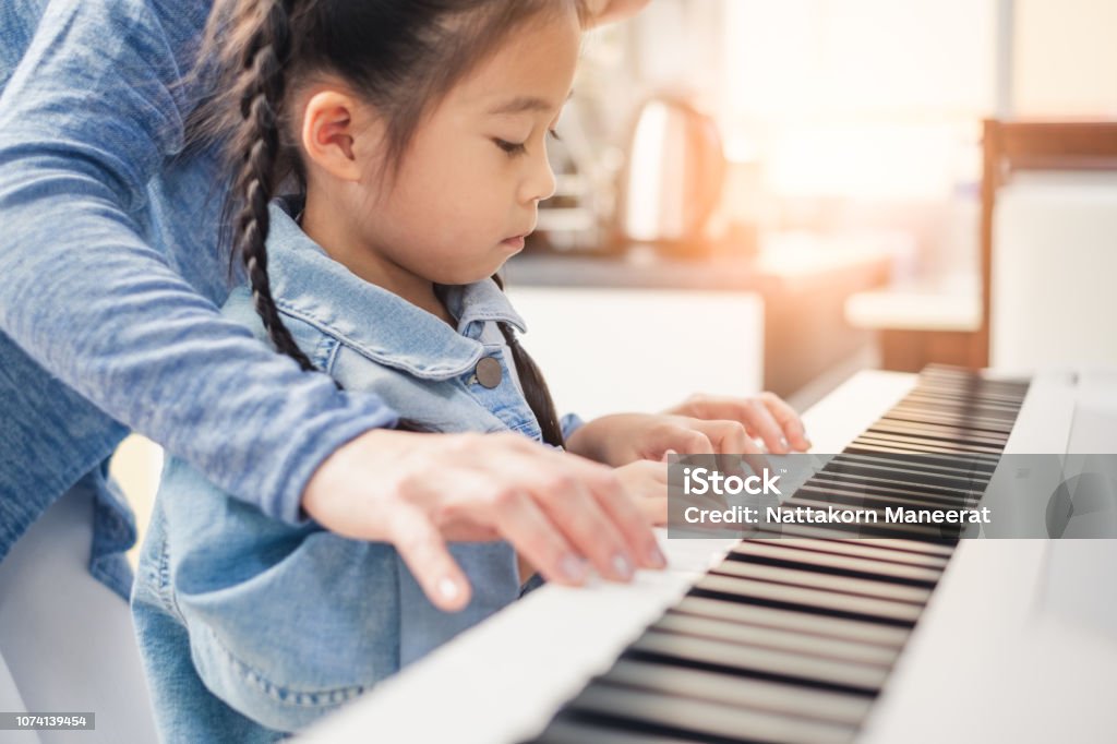 Asian young pianist teacher teaching girl kid student to play piano, music education concept Child Stock Photo