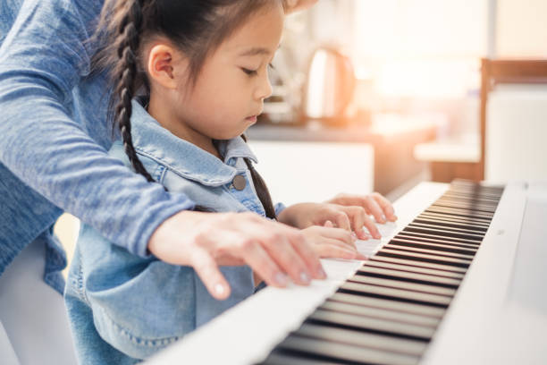 Asian young pianist teacher teaching girl kid student to play piano, music education concept Asian young pianist teacher teaching girl kid student to play piano, music education concept musical instrument photos stock pictures, royalty-free photos & images