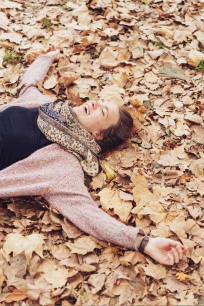 istock laughing woman lying on autumn leaves 1074145348