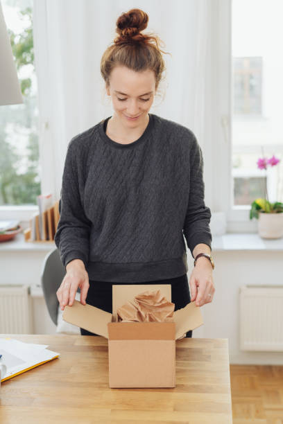 istock Young woman opening a brown cardboard box 1074145706