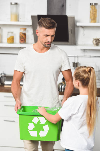 istock father and daughter putting empty plastic bottles at green recycle box at kitchen 1074145884