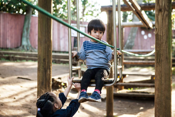 istock Young Siblings playing with park ropeway type playground equipment. 1074146318