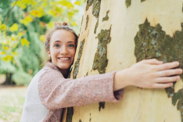 istock Smiling happy young woman hugging a tree 1074147784