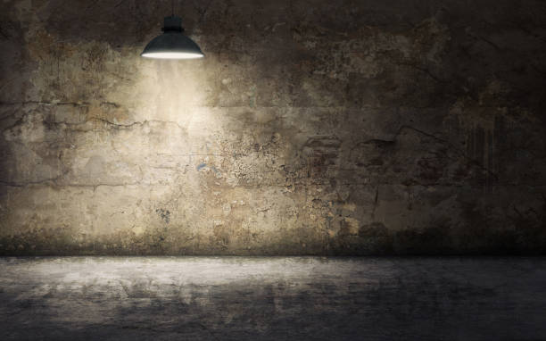 istock Dark empty room with old damaged concrete wall and ceiling lamp shining. 3d rendering 1074148426