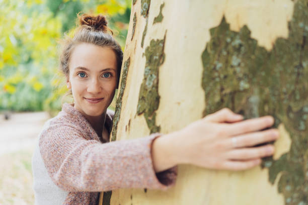 istock Pretty young woman hugging a tree trunk 1074149964