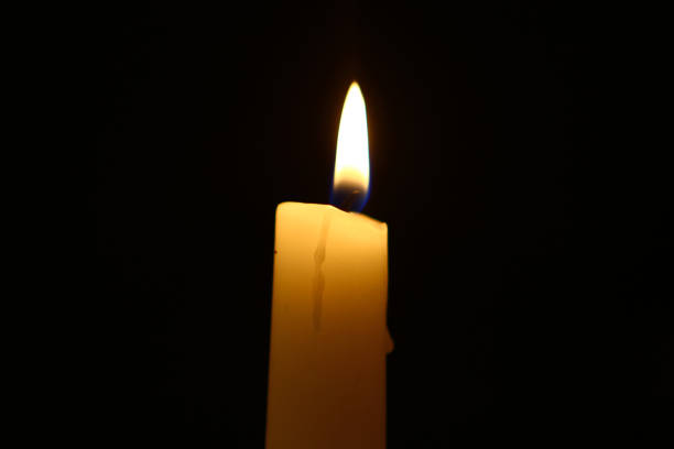 istock tiny paraffin glowing yellow candle with bright fire on the black background. 1074150520