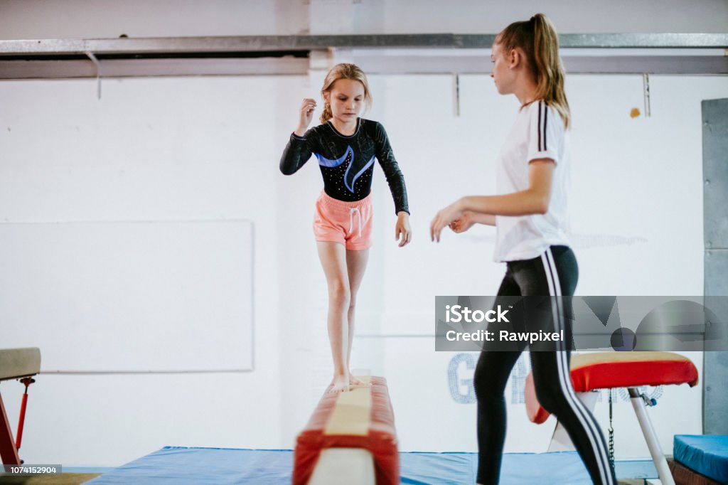 Young gymnast balancing on a balance beam Gymnastics Stock Photo