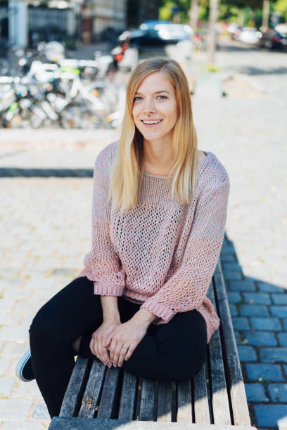 istock Young woman sitting on a bench on a cobbled road 1074155050