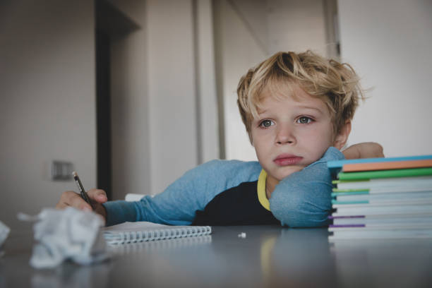 istock little boy tired stressed of reading, doing homework 1074157786