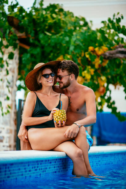istock Young couple drinking pineapple cocktail in a pool 1074160606