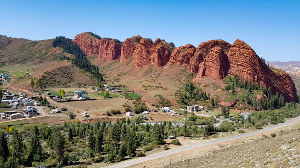 istock A red rocks under blue sky with green trees and houses. 1074166138