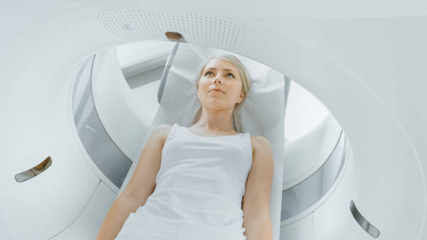 Female Patient Lying on a CT or MRI Scan, Bed is Moving inside Machine Scanning Her Body and Brain. In Medical Laboratory with High-Tech Equipment. Female Patient Lying on a CT or MRI Scan, Bed is Moving inside Machine Scanning Her Body and Brain. In Medical Laboratory with High-Tech Equipment. pet scan photos stock pictures, royalty-free photos & images