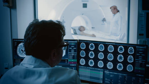 istock In Medical Laboratory Patient Undergoes MRI or CT Scan Process under Supervision of Radiologist, in Control Room Doctor Watches Procedure and Monitors Brain Activity. 1074166406