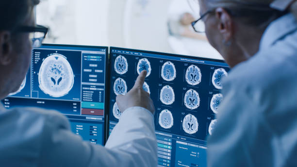 nella sala di controllo medico e radiologo discutono della diagnosi durante la procedura di osservazione e monitorano la visualizzazione dei risultati delle scansioni cerebrali, nel paziente in background viene sottoposto a risonanza magnetica o procedura  - esaminare immagine foto e immagini stock