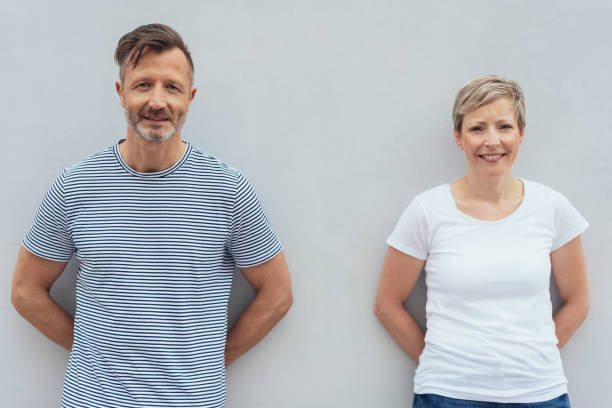 Middle-aged couple posing against a white wall