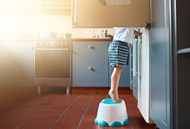 Growing up and learning to make his own food Shot of an unrecognizable little boy looking in the refrigerator at home tiptoe stock pictures, royalty-free photos & images