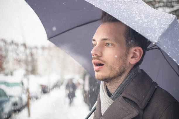 jovem bonito com guarda-chuva, respirando o ar quente na neve do inverno - vapor da respiração - fotografias e filmes do acervo