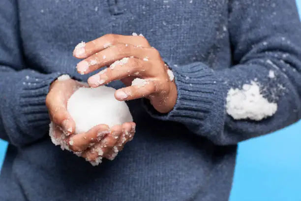 Close up snowball in playful man's hands ready to fight.