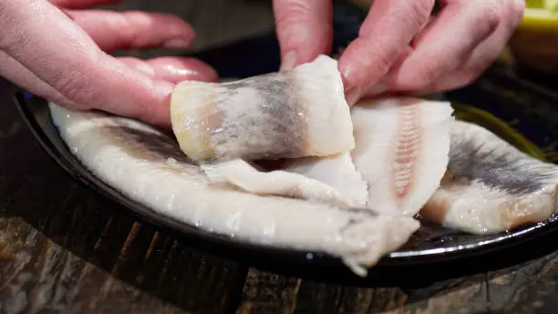 Preparing homemade rollmops, traditional European herring snack