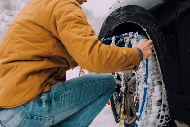 Man installing winter tires Mechanic installing chains on a car in the middle of the road slippery unrecognizable person safety outdoors stock pictures, royalty-free photos & images