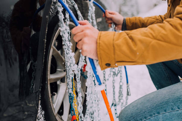 Person installing chains on a car Unrecognizable man putting winter chains on his car tires slippery unrecognizable person safety outdoors stock pictures, royalty-free photos & images