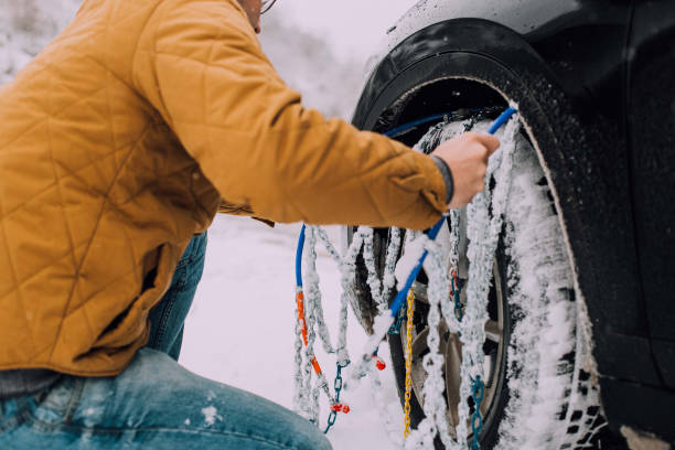 Man installing chains on a car Unrecognizable man putting chains on winter tires on his car slippery unrecognizable person safety outdoors stock pictures, royalty-free photos & images