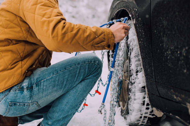 Man putting chain on a tire Mechanic installing winter tires on a car slippery unrecognizable person safety outdoors stock pictures, royalty-free photos & images