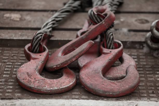 istock Hoist chains, chain hook wheel alignment, Chain hoists for heavy lifting, tow black crane hooks on a floor with white dust of construction Site 1074202376