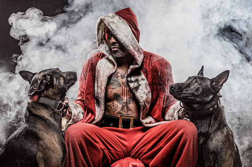 Portrait of weapon wielding tattooed bad ass Black Santa Claus with his dogs