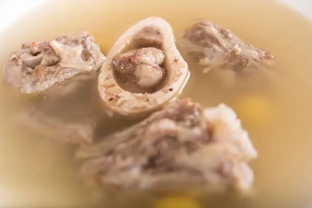 Bone marrow soup,  served in a white bowl,  light background,  isolated