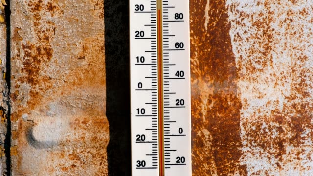 Thermometer on a rusty wall which shows 30 degrees of heat.