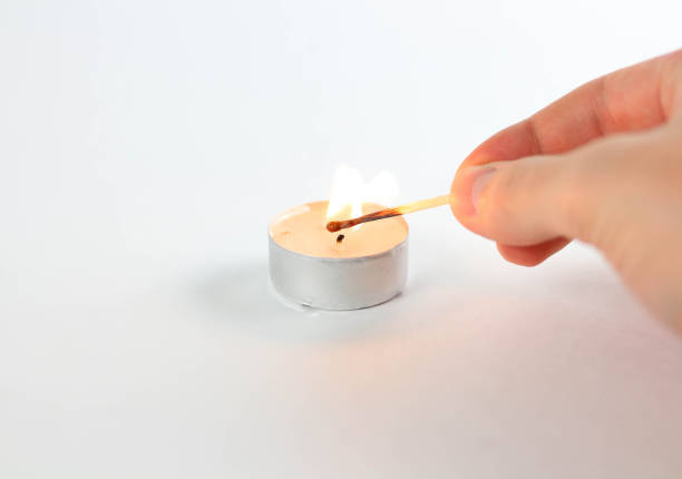istock A match ignites the candle. Close up. Isolated on white background 1074211472