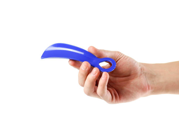 istock Hand holding blue Shoe spoon. Close up. Isolated on white background 1074211496