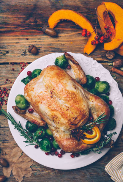 istock Thanksgiving roasted chicken with Brussels sprouts and spices on a rustic wooden table. Thanksgiving dinner or fall dinner concept background with autumn leaves. Thanksgiving table setting background. 1074213250