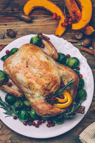 istock Thanksgiving roasted chicken with Brussels sprouts and spices on a rustic wooden table. Thanksgiving dinner or fall dinner concept background with autumn leaves. Thanksgiving table setting background. 1074213276
