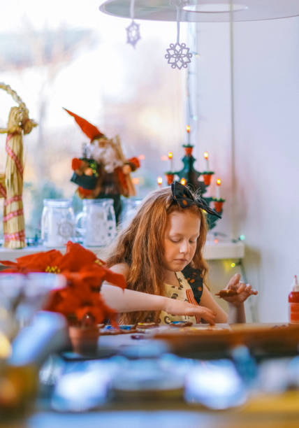 istock Cute girl decorating gingerbread cookies at table 1074219422