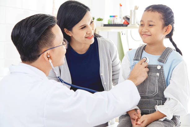 istock Professional doctor wearing white coat using stethoscope to examine kid patient with her mother in hospital background 1074219494