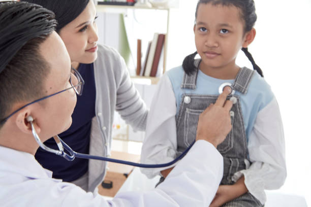 istock Professional doctor wearing white coat using stethoscope to examine kid patient with her mother in hospital background 1074219700