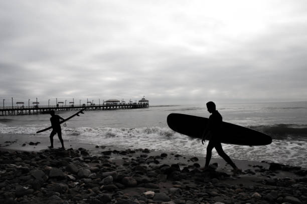 istock Silhouette of two surfers carrying surfboard 1074219740