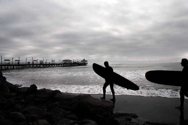 istock Silhouette of two surfers carrying surfboard 1074219746