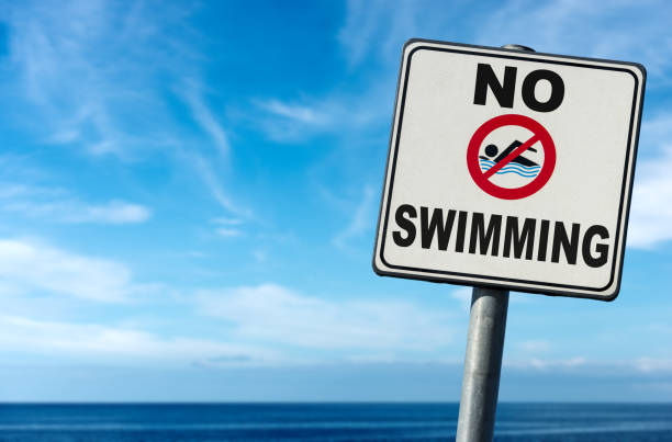 No Swimming - Sign on a Blurred Blue Sea stock photo