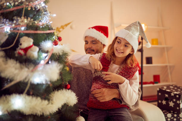 istock Father and daughter decorating cristmas tree together at home. 1074234658