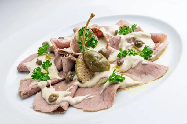 Dish of veal slices with mayonnaise of tuna and capers isolated on white background