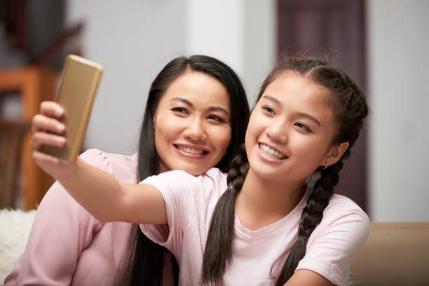 istock Content girl with mother taking selfie at home 1074240036