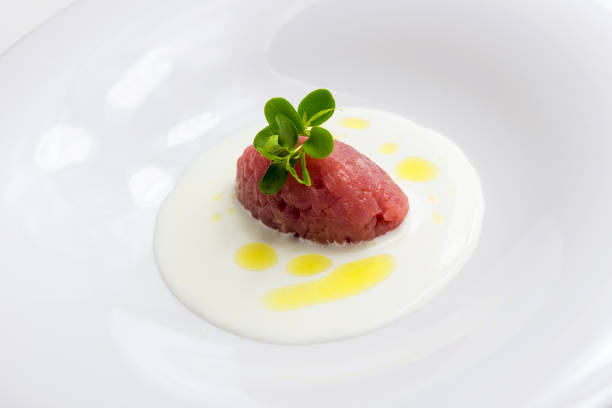 Dish with raw red tuna quenelle on cream cheese isolated on white background