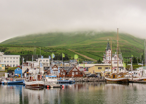 Picturesque panorama of town Husavik, colorful houses and church reflect in the sea water, Northern Iceland. Popular tourist destination in Europe